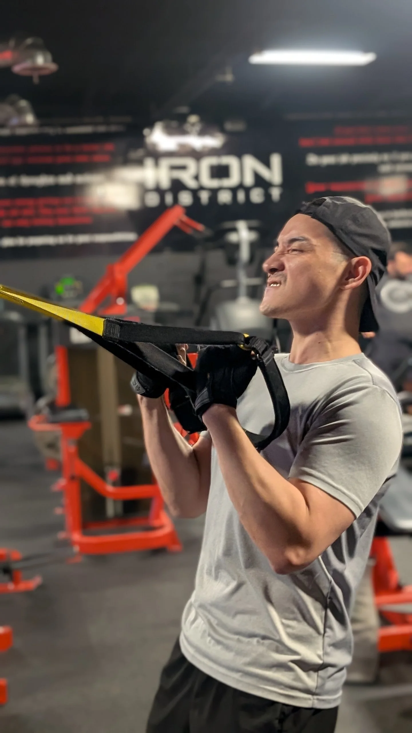 A smiling man using suspension-training straps.